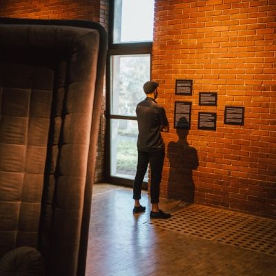 Wernisaż 9 Triennale Młodych,widok ogólny galeri, widoczna postać mężczyzny oglądającego serie prac na ścianie - Zdjęcie udostępnione dzięki uprzejmości p. Piotra Czyża