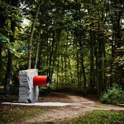 Na zdjęciu nowa rzeźba autorstwa Krzysztofa M. Bednarskiego umieszczona w przestrzeni parku, duży granitowy blok, stalowa rura w kolorze czerwonym przechodząca na przestrzał fot. Katarzyna Purchalak 