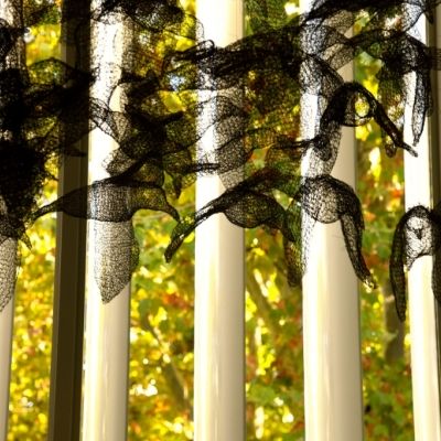 Praca Young W. Song,Anflug,  ażurowe ptaki z dzianiny metalowej na tle okna z widokiem na jesienne drzewa  fot. Czekalska Golec 